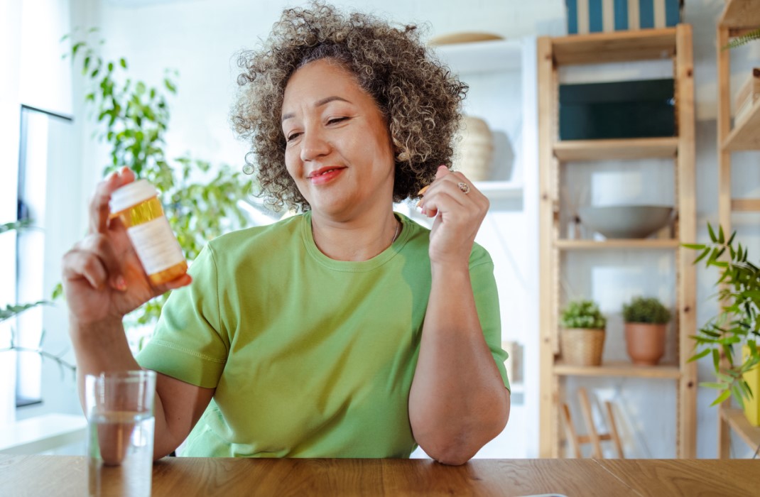 An older woman reads a prescription bottle of pills.